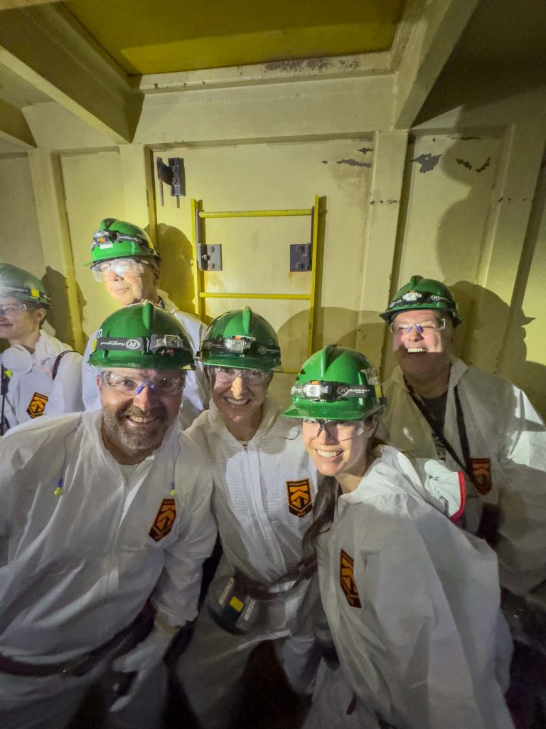 Nutrien employees in green hard hats smiling at the camera.